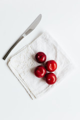 Overhead view of red plums on white vintage napkin