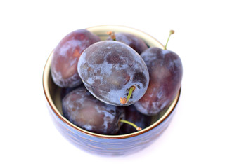 Fresh plums in a blue bowl on a white background