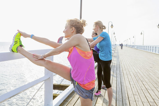 Women on jetty stretching legs