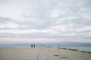 Sunset in the mountains with a beautiful view of the sea and rocks and a couple walking far away