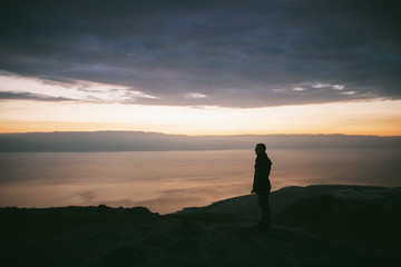 Sunrise in the mountains with a beautiful view of the sea and rocks and a lonely person watching it