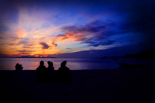Three girls sitting watching the sunrise at ang thong beach.Thailand. 