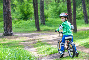 Happy cute blond kid boy having fun his first bike on sunny summer day, outdoors.  child making sports. Active leisure for children.