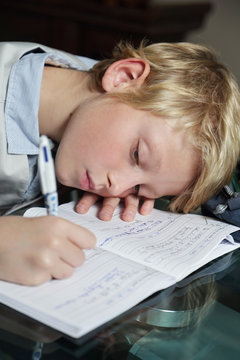 enfant gar&ccedil;on blond faisant ses devoirs scolaires