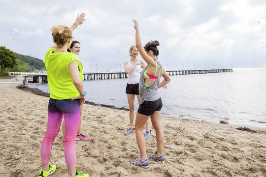 Group of women on beach doing warm up exercises