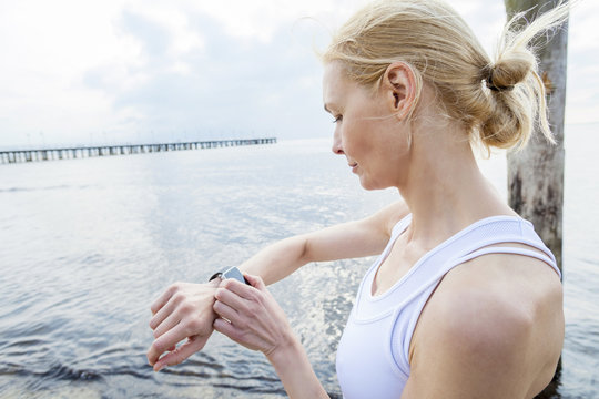 Woman on beach checking running watch