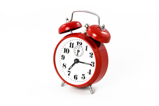 Round red alarm clock on white background isolated. The image of the retro clock shows a quarter past seven.