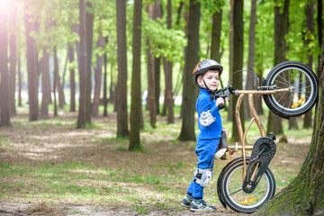 Happy cute blond kid boy having fun his first bike on sunny summer day, outdoors.  child making sports. Active leisure for children.  wear safety helmet.  is smiling and cicling.