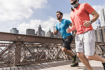 USA, New York City, two men running on Brooklyn Bridge