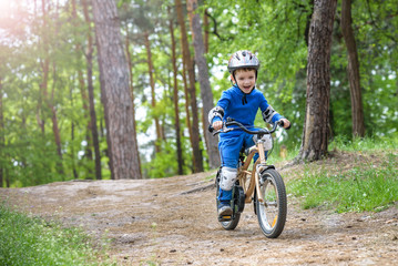 Happy cute blond kid boy having fun his first bike on sunny summer day, outdoors.  child making...