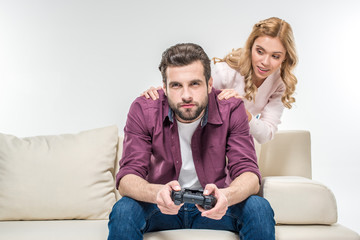 Woman looking at man playing with joystick