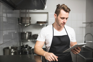 Chef in the kitchen reading on tablet