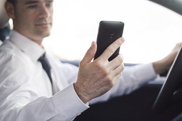 Businessman using his smartphone in the car