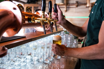 Bartender in coffee shop pouring beer from tap