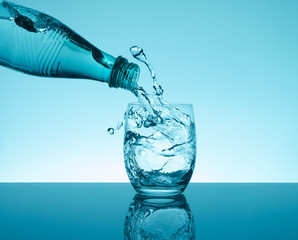 Bottle with creative splashing water in the glass