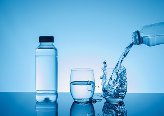 Bottle with creative splashing water in the glass