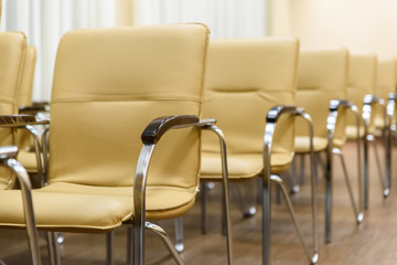 Rows of metal chairs at the conference in an empty room. Front view