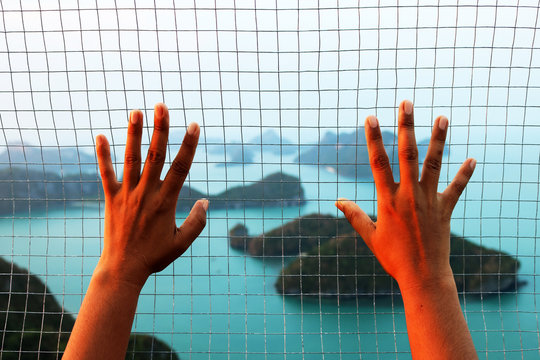The hand holding the steel mesh with blurry background image view of ang thong island. 