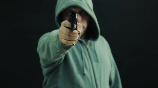 Nervous junkie in green hoodie points gun and fires