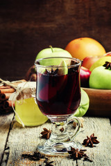 Hot mulled wine with apple and cinnamon, vintage wooden backgrou