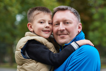 Proud father hugging his son outside