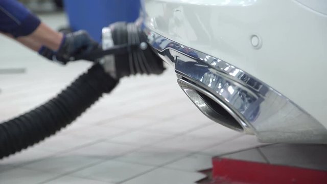 Workers install pipe to exhaust outlet of cars indoors