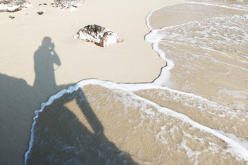 The shadow of the photographer on the beach and sea. 