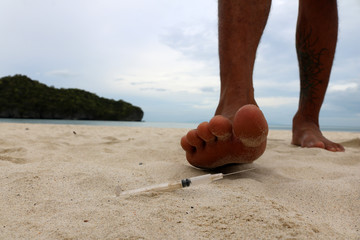Foot step on broken glass bottle on the beach.