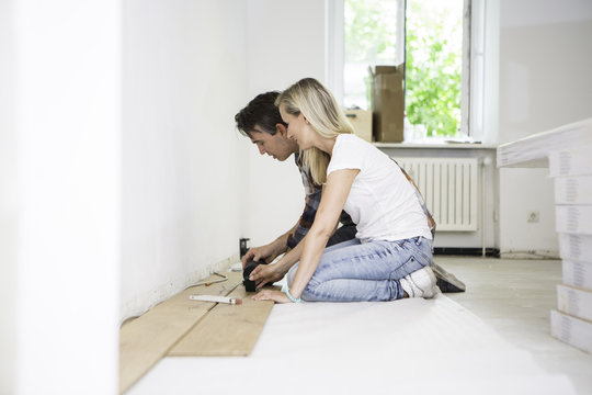 Young couple laying parquet in apartment
