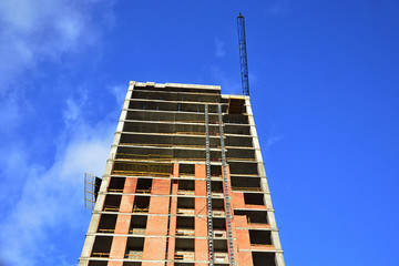 Fototapeta premium Construction of a skyscraper monolith and brick construction elements from a number of tower crane.