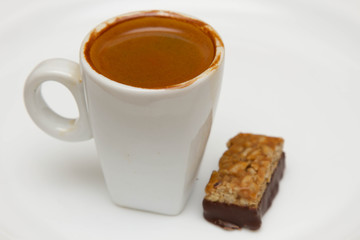 cup of hot espresso and candy on a white background