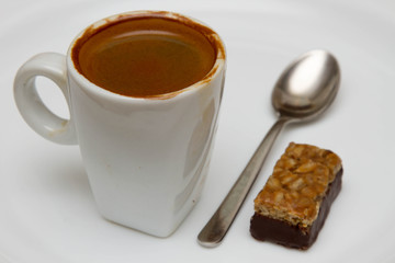 cup of hot espresso and candy on a white background