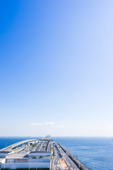 Fototapeta premium panoramic bird eye top aerial view with beautiful sea level with highway road under dramatic clear glow and fantasy blue sky in Umi Hotaru parking area island Tokyo bay aqua line, Japan