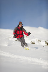 Happy skier with knit hat in action skiing downhill