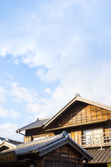 culture concept - japanese traditional historical wooden old house under golden sun and morning blue cloudy sky