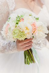 bride with a wedding bouquet of roses and peonies