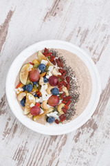 oatmeal with fruit, nuts and chia in plate, vertical, top view