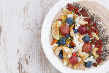 oatmeal with fruit, nuts and chia in plate, top view, closeup