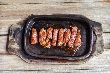 grilled beef tenderloin steak in a hot pan on wooden vintage table