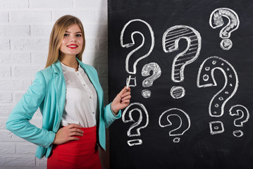 An attractive young woman with chalk and question mark on a background