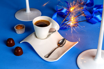 кружка кофе с горящими бенгальскими огнями и шоколадными конфетами