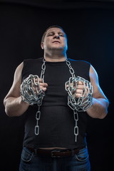 Actor Brutal man with a chain in his hands on a black background.