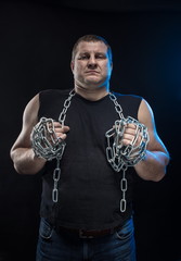 Actor Brutal man with a chain in his hands on a black background.