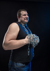 Actor Brutal man with a chain in his hands on a black background.