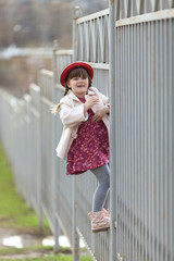 child girl with pigtails in hat  climbs on  fence