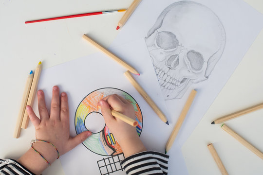 Girl coloring a simple sketch of a skull