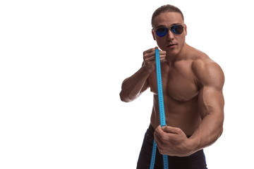 Portrait of a brutal man bodybuilder in sunglasses with a blue measuring tape on a white background