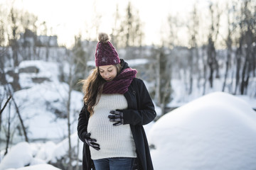 Fototapeta premium Young happy pregnant woman in snowy forest