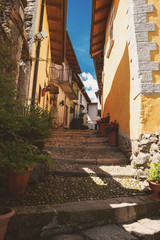 Fototapeta na wymiar Narrow town street at daytime. Green plants and stone stairs. Explore old district of Stresa.