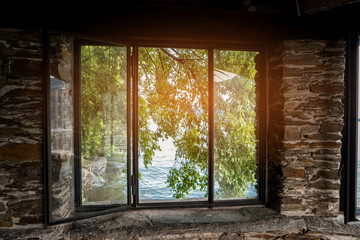 Nature behind window. Tree branches and water. Old house on the shore.